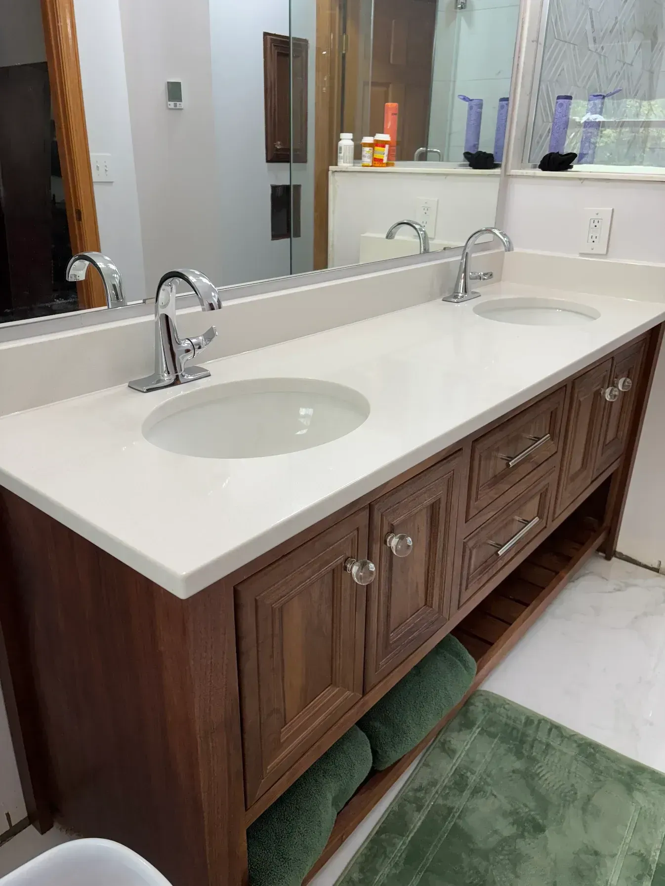 Bathroom vanity with two sinks, a white countertop, and dark wood cabinets with chrome faucets.