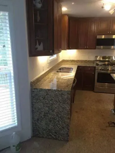 Kitchen with granite countertops and dark wooden cabinets, next to a window.