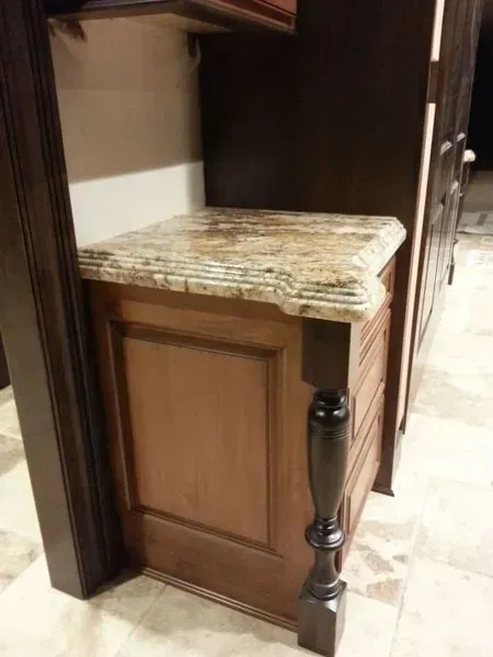 Wooden cabinet with granite countertop in kitchen.