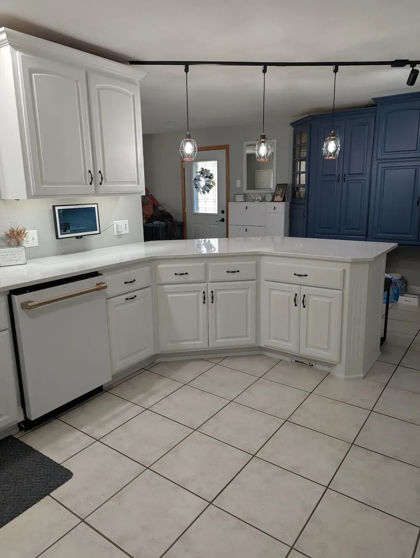 White kitchen with curved island, white cabinets, copper dishwasher, and blue pantry.