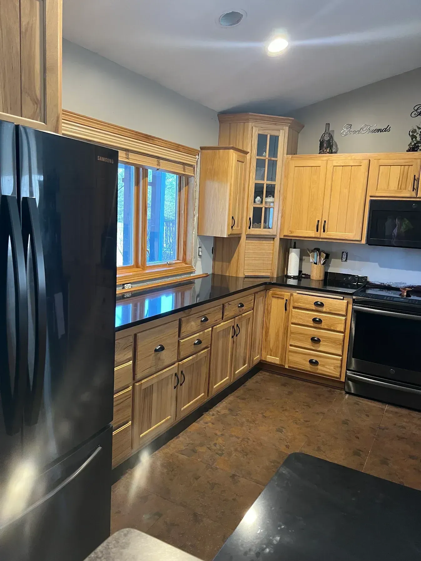 Kitchen with light wood cabinets, black countertops, and stainless steel appliances.