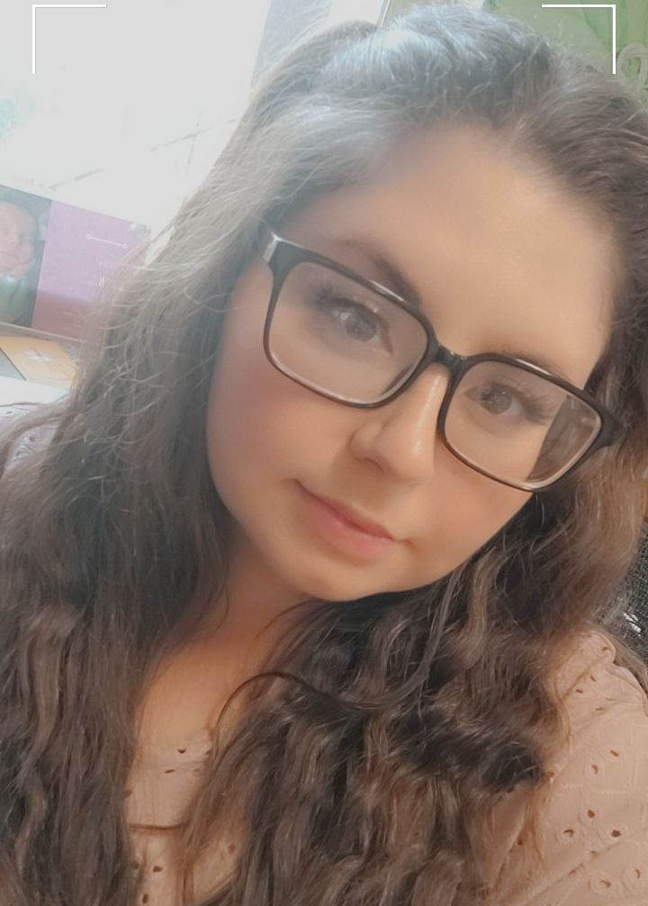 A young woman wearing glasses is taking a selfie.