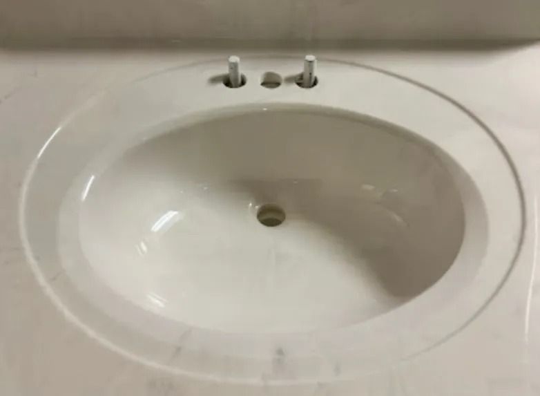 White bathroom sink with a chrome faucet and drain hole close-up