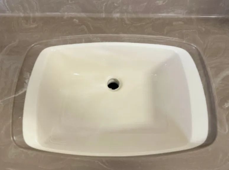 White rectangular sink basin with a central drain hole inside a clear tray.