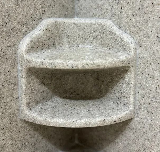 White plastic wall-mounted holder with two open compartments on a speckled gray background