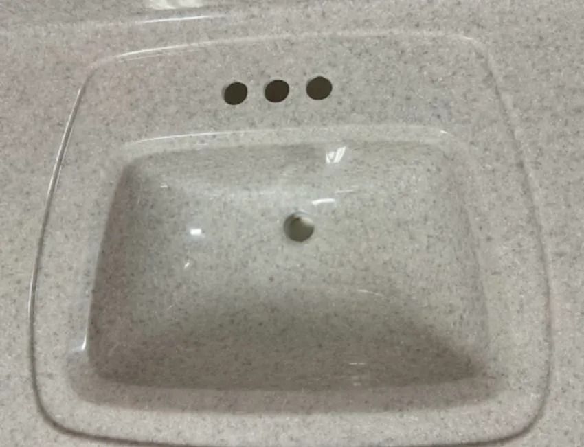 White porcelain sink with three faucet holes and a drain hole, viewed from above.