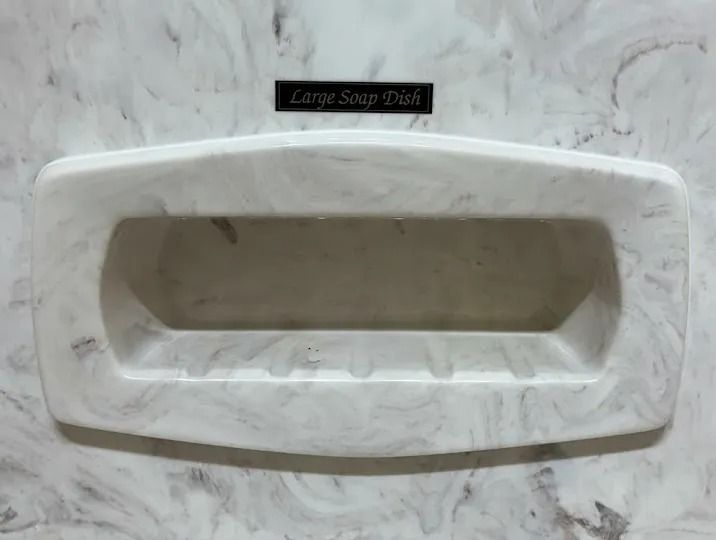 White rectangular wall-mounted soap dish with recessed center on marble tile background