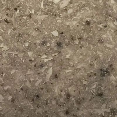 Close-up of a beige speckled stone or terrazzo surface with small gray and white flecks