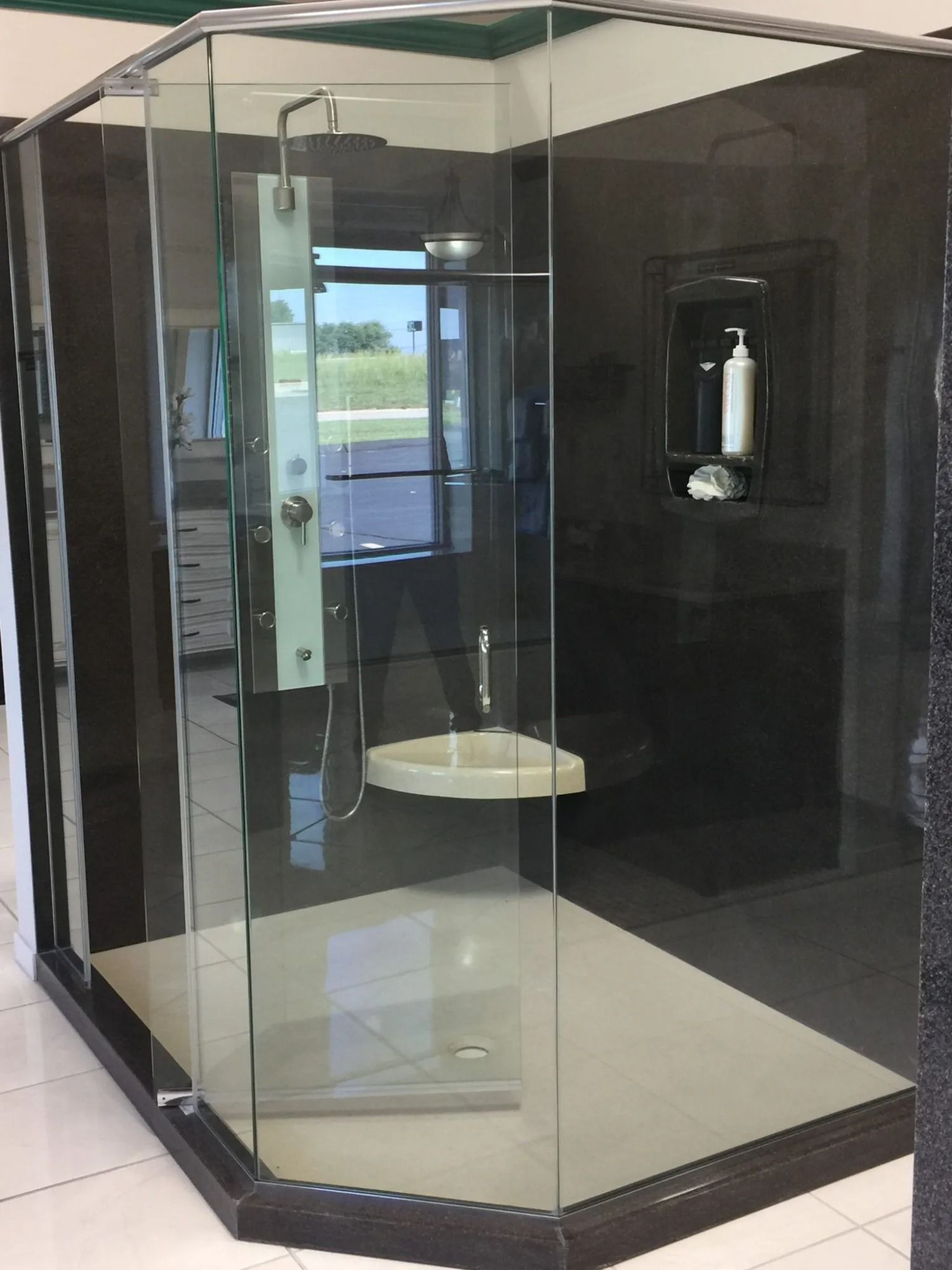 Glass walk-in shower with dark tiled walls, white floor, and built-in corner shelves