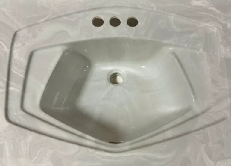 White bathroom sink with three faucet holes and a central drain, viewed from above