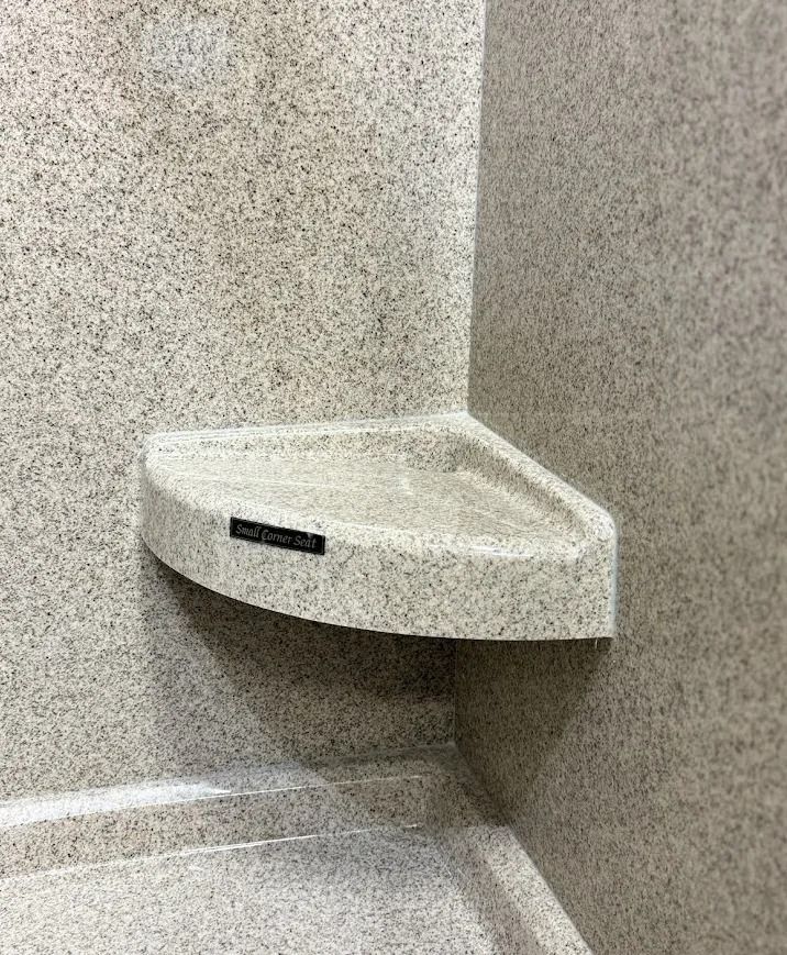 White corner sink in a speckled gray restroom stall