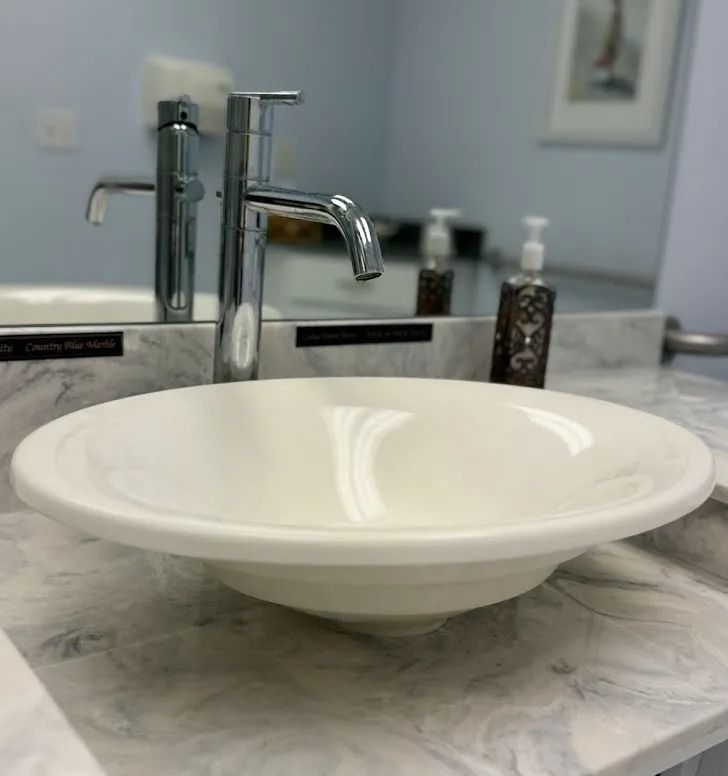 White bowl sink with chrome faucet on a marble bathroom countertop.