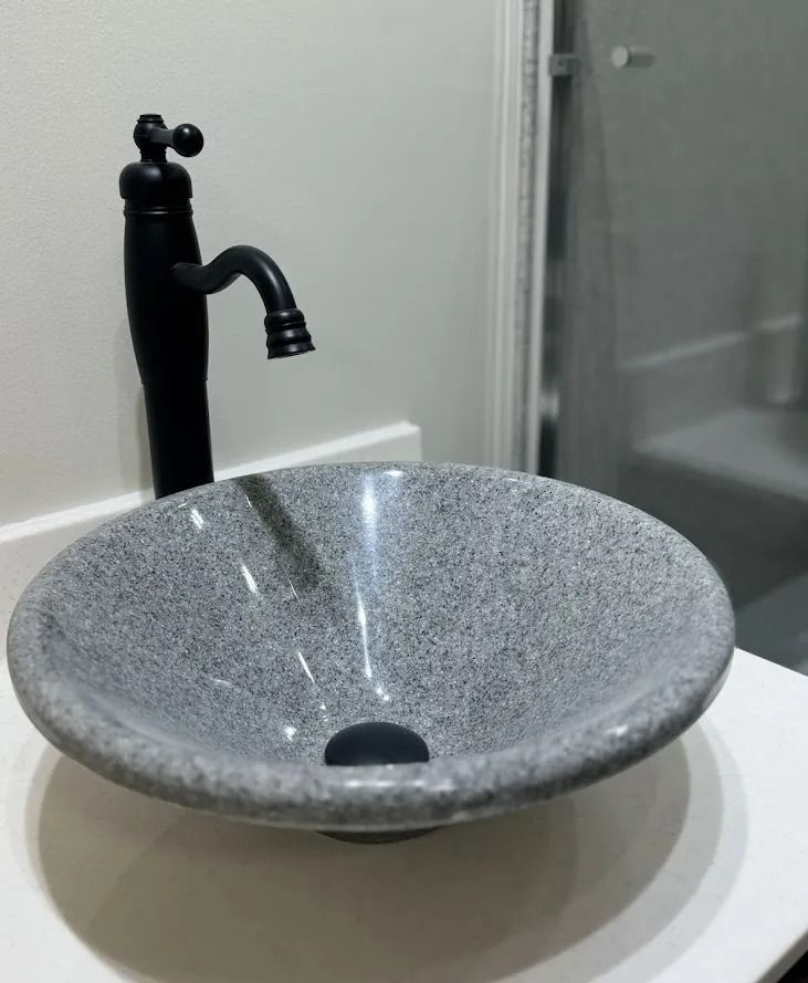 Gray speckled stone basin sink with black faucet in a bathroom