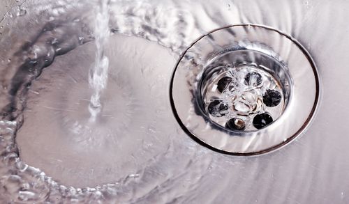 Stainless steel sink drain with swirling water and visible ripples