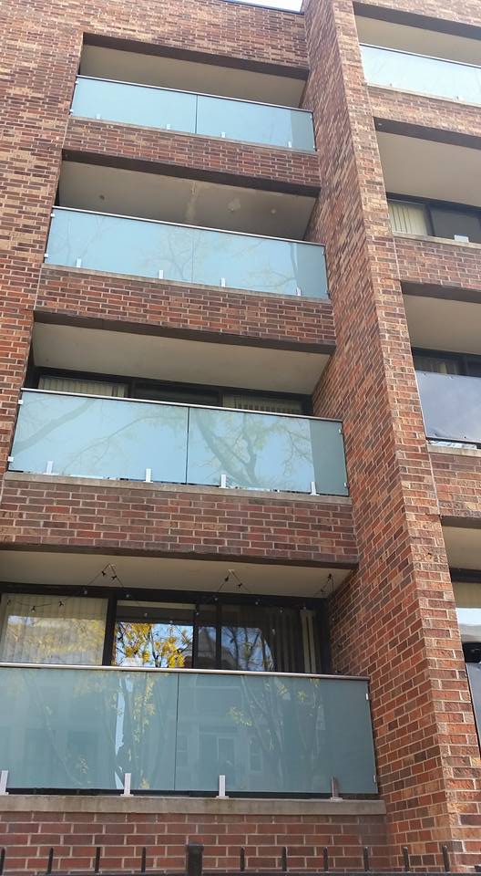 A brick building with a glass railing on the balconies