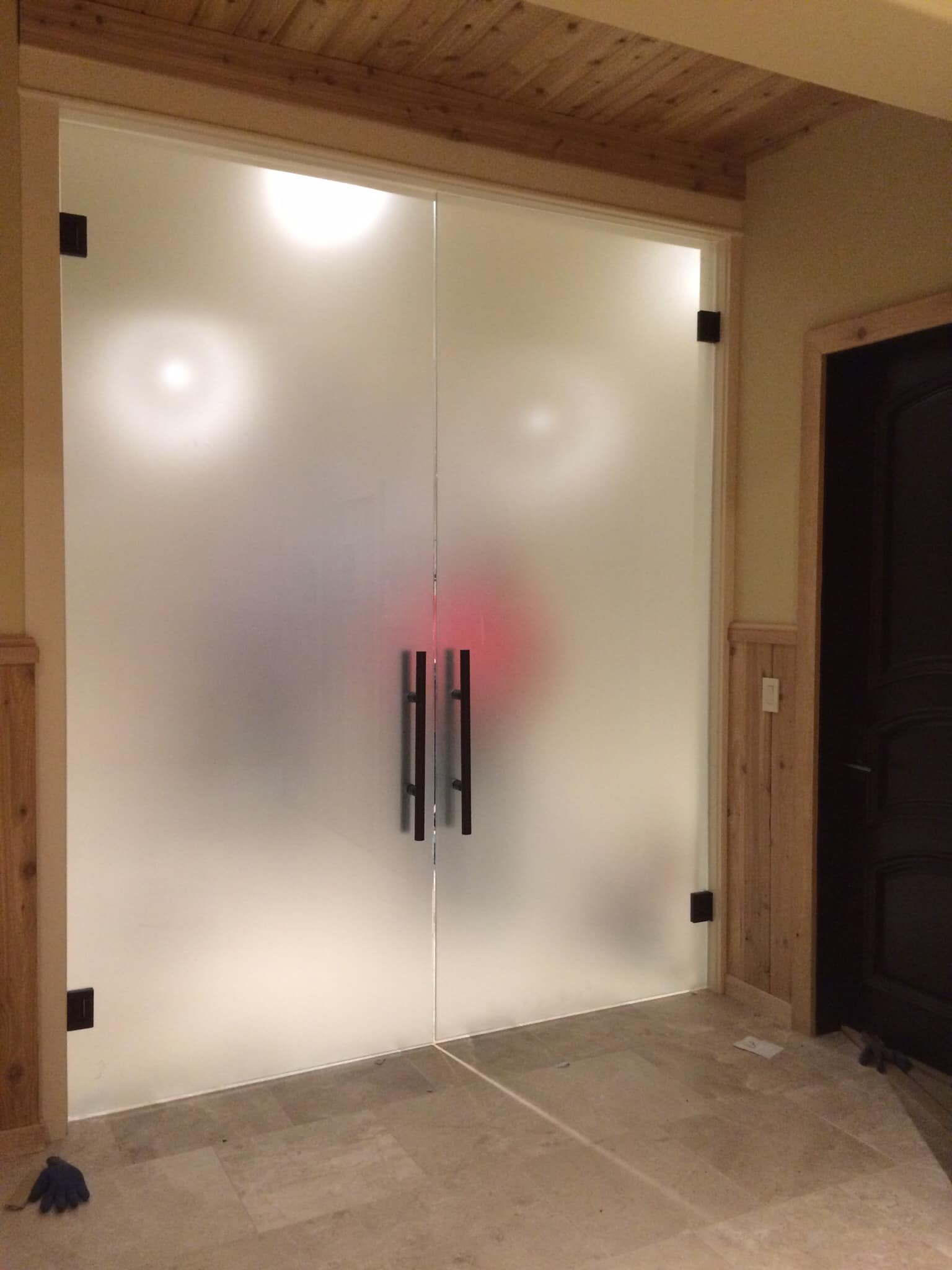 A pair of frosted glass doors with black handles in a room.