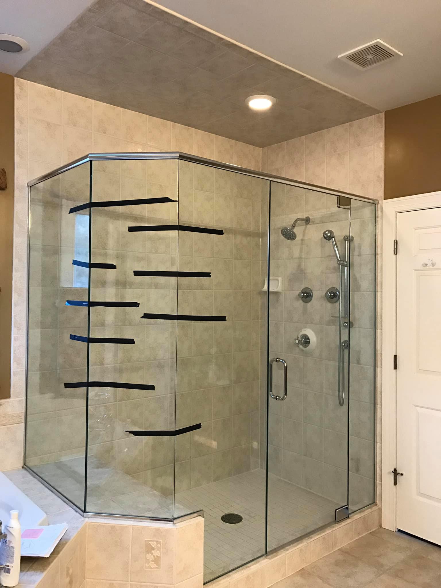 A bathroom with a shower stall with sliding glass doors and a shower head.