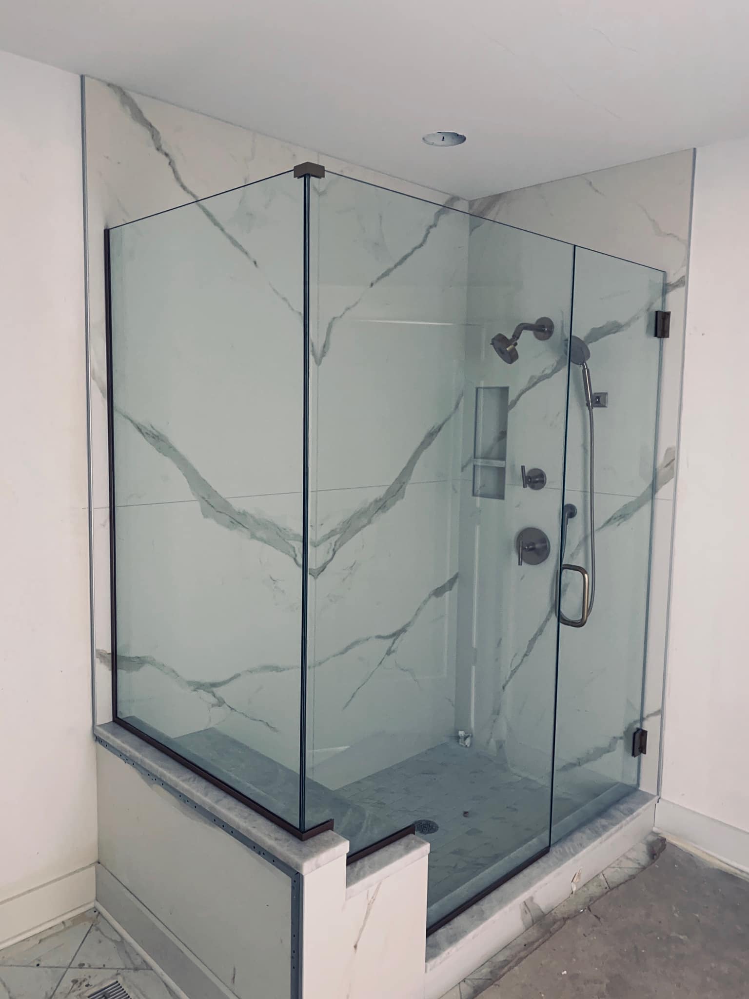 A bathroom with a walk in shower with a marble wall.
