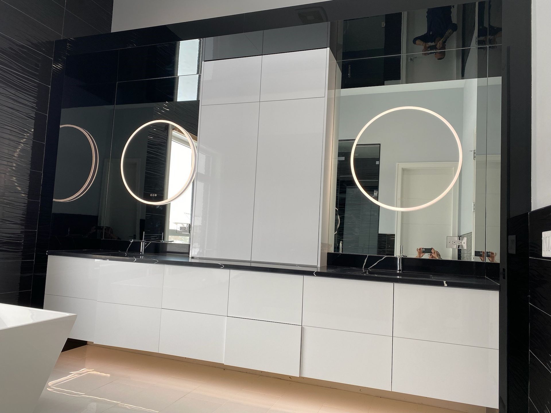 A bathroom with two sinks , two mirrors and a bathtub.