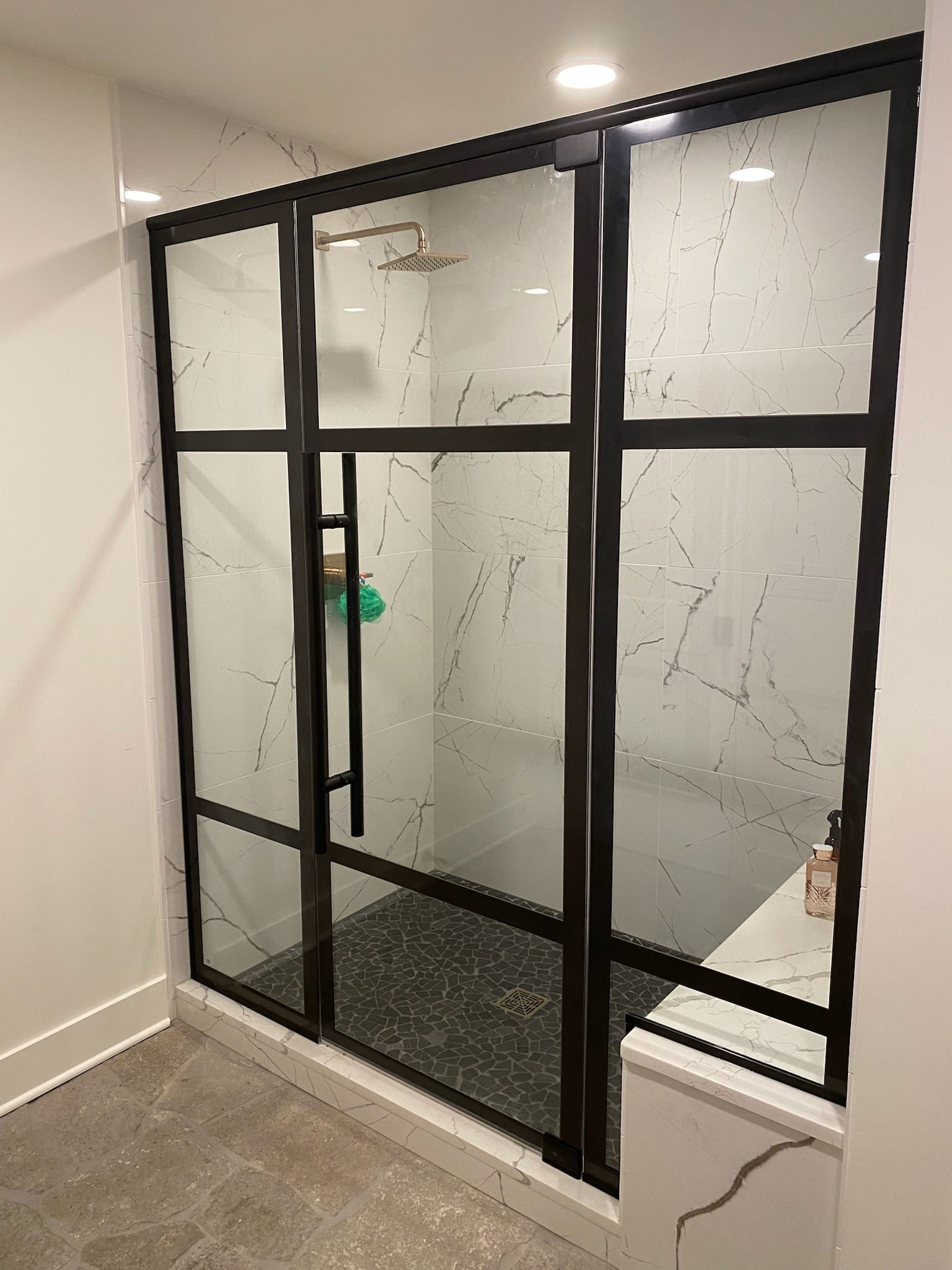 A bathroom with a walk in shower with a black frame.