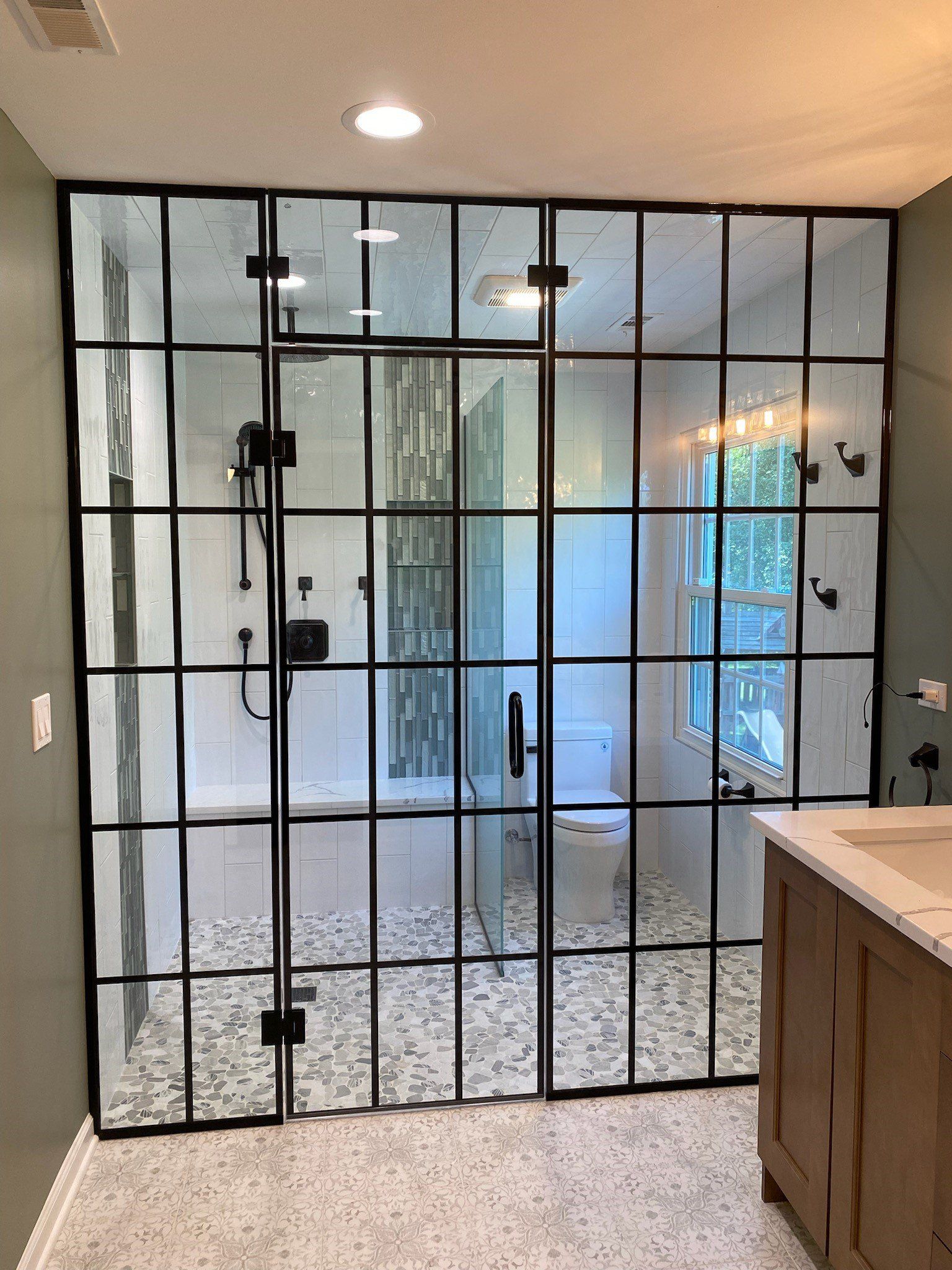 A bathroom with a glass shower door and a sink.