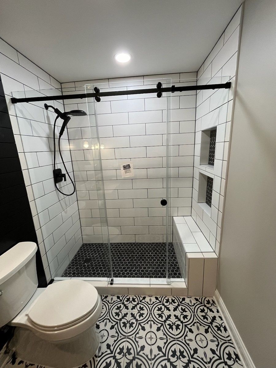 A bathroom with a toilet, shower, and bench