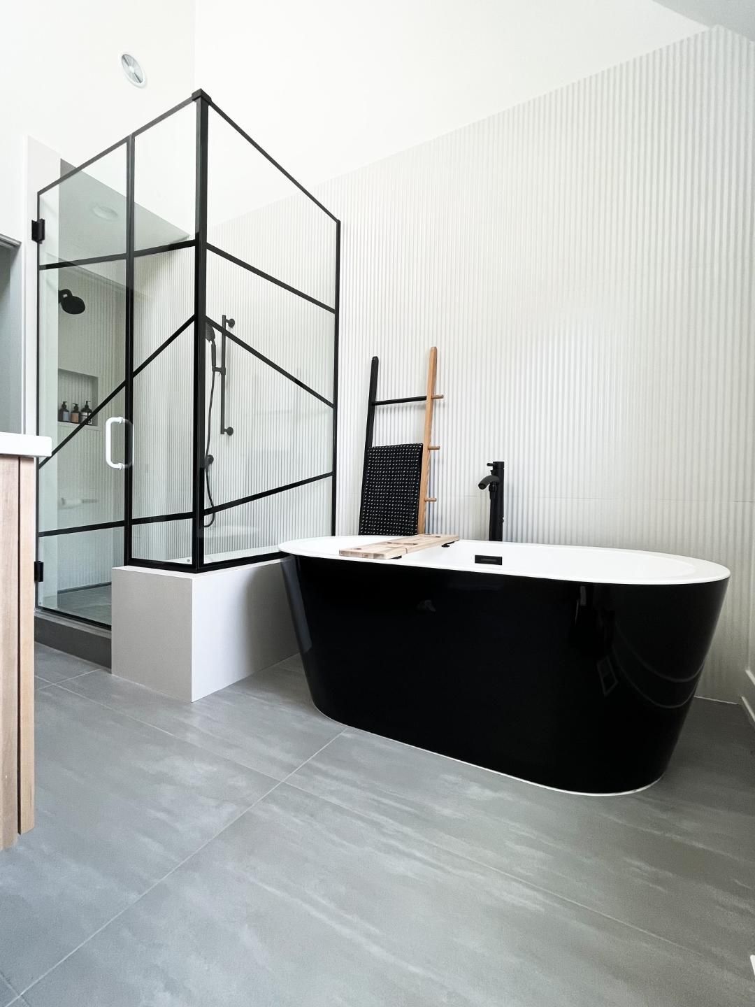 A bathroom with a black tub and a shower stall