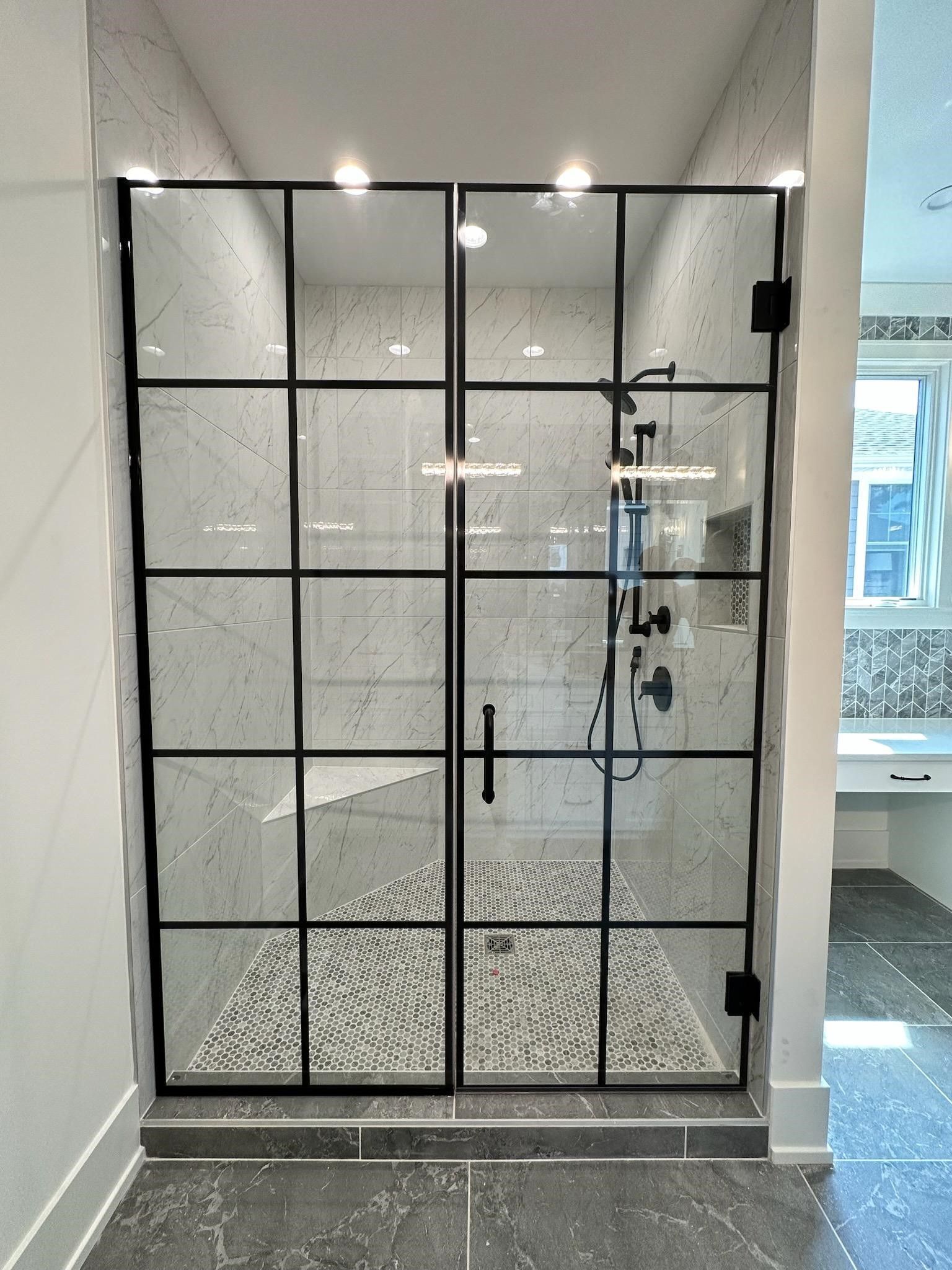 A bathroom with a walk in shower with a black frame