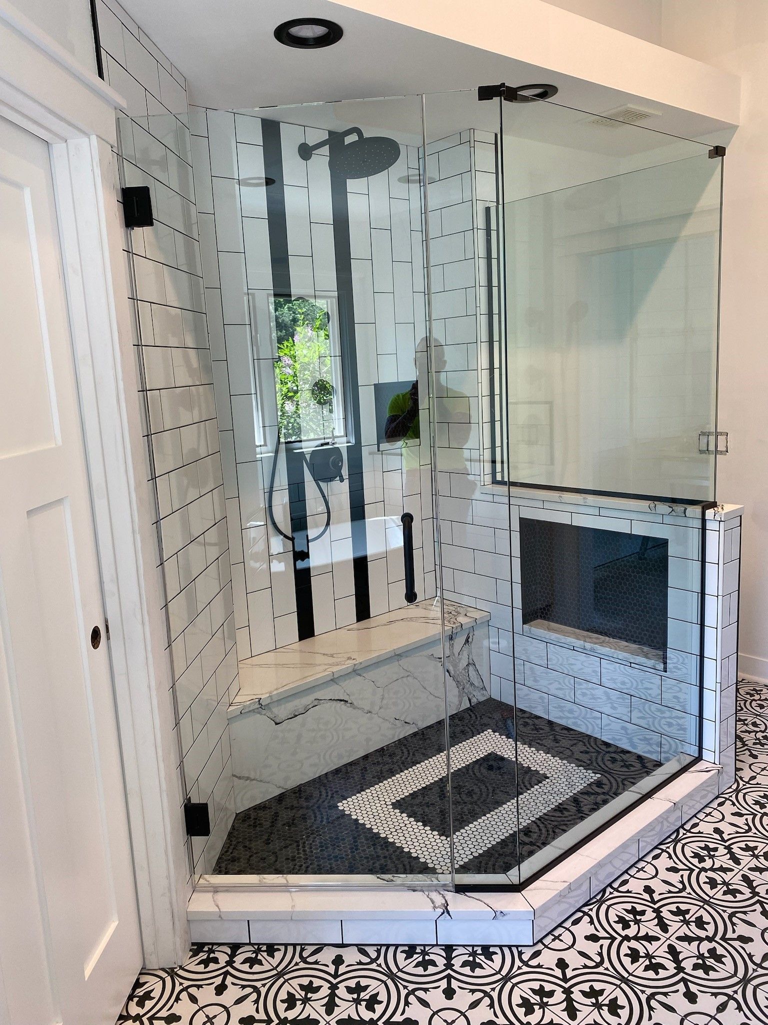 A bathroom with a walk in shower with a black and white tile floor