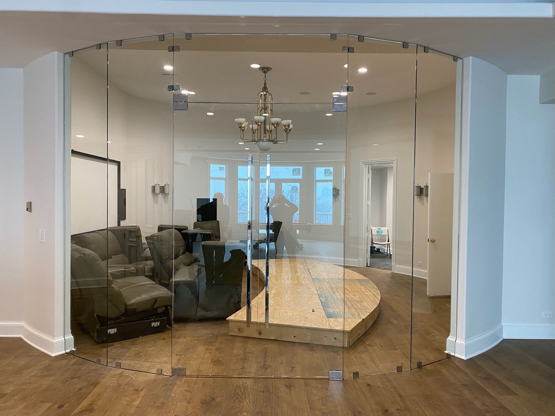 A living room with a curved glass wall and a wooden floor