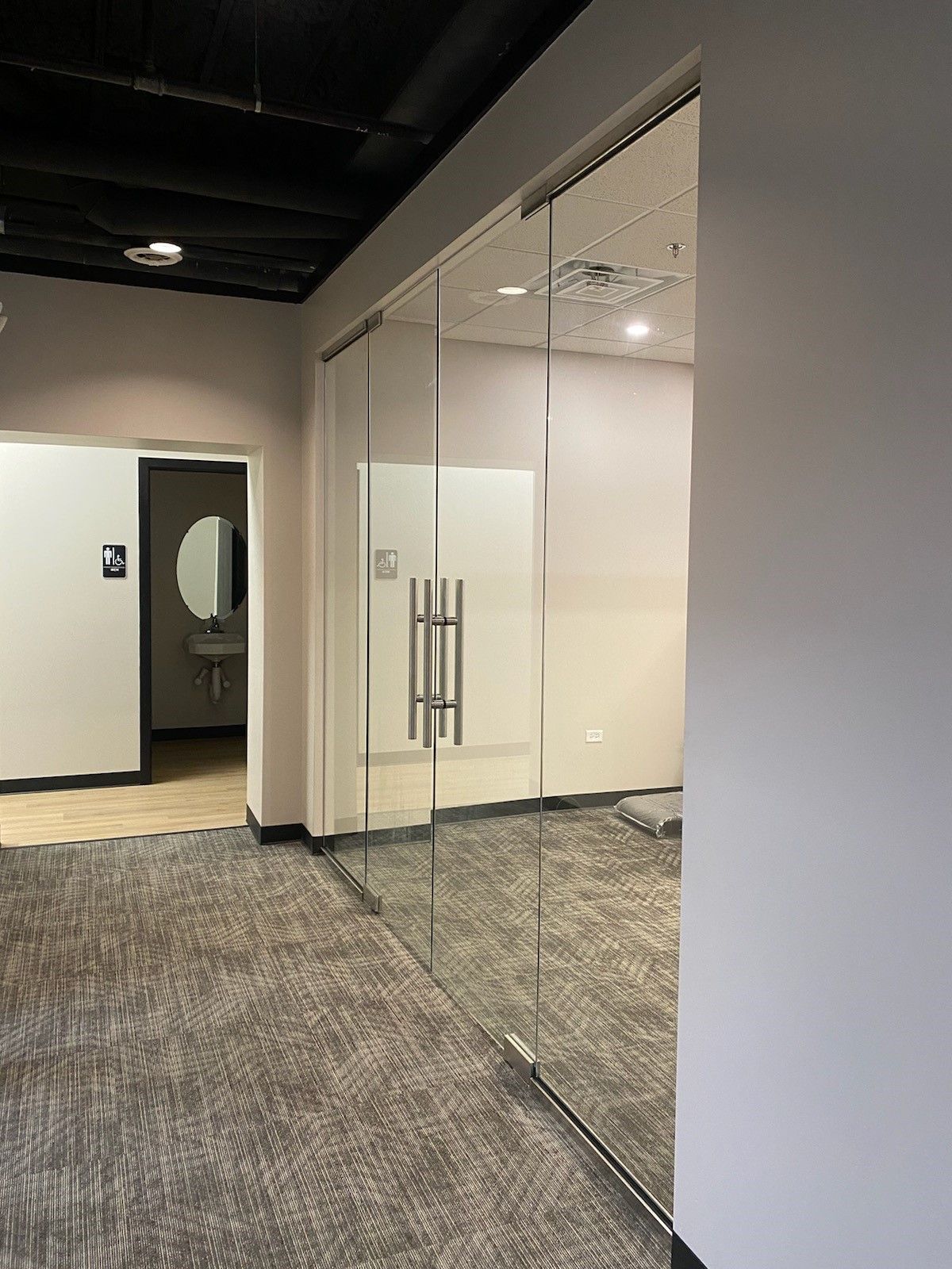 A hallway with sliding glass doors and a bathroom in the background