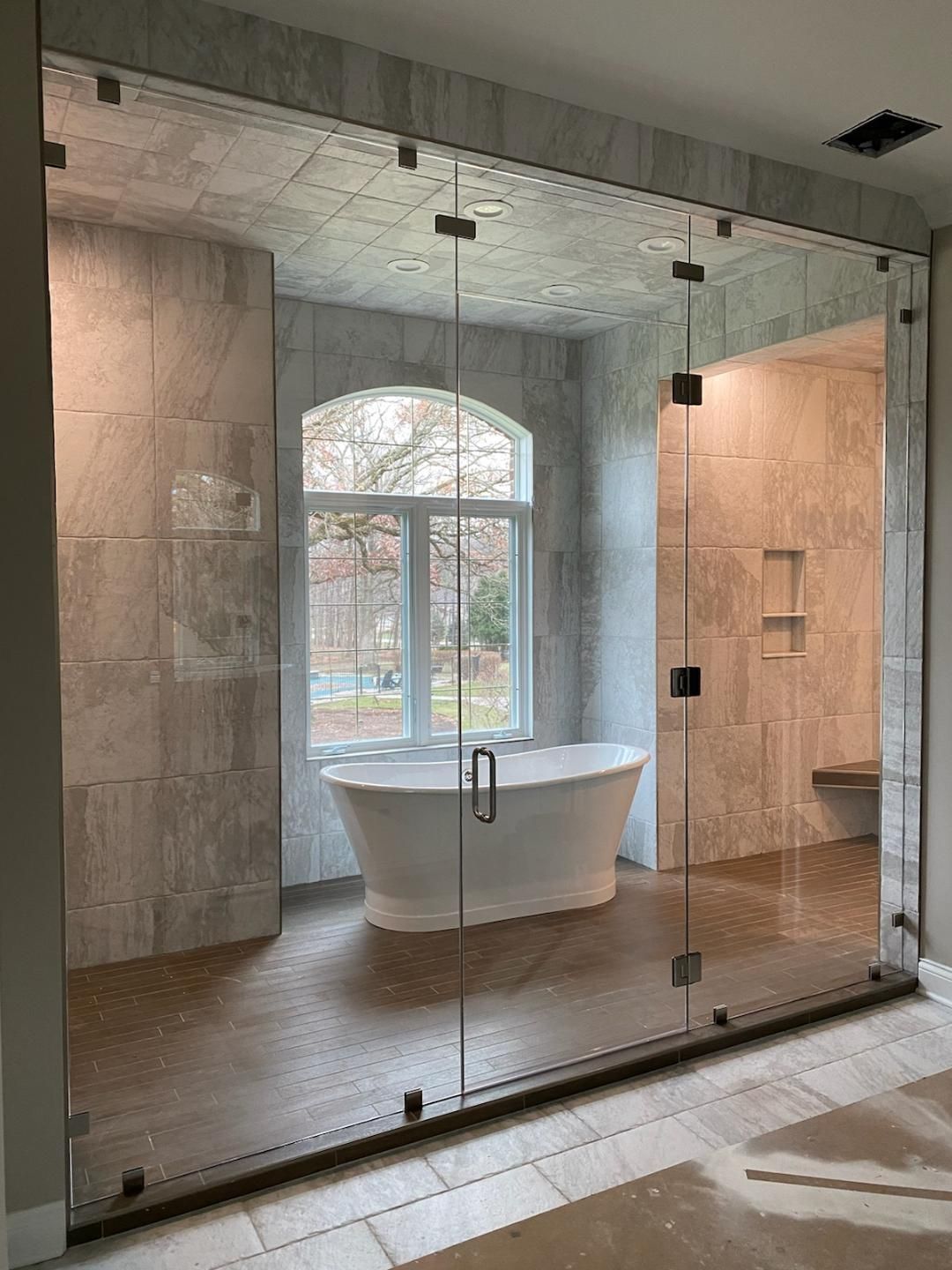 A bathroom with a tub and shower behind glass doors