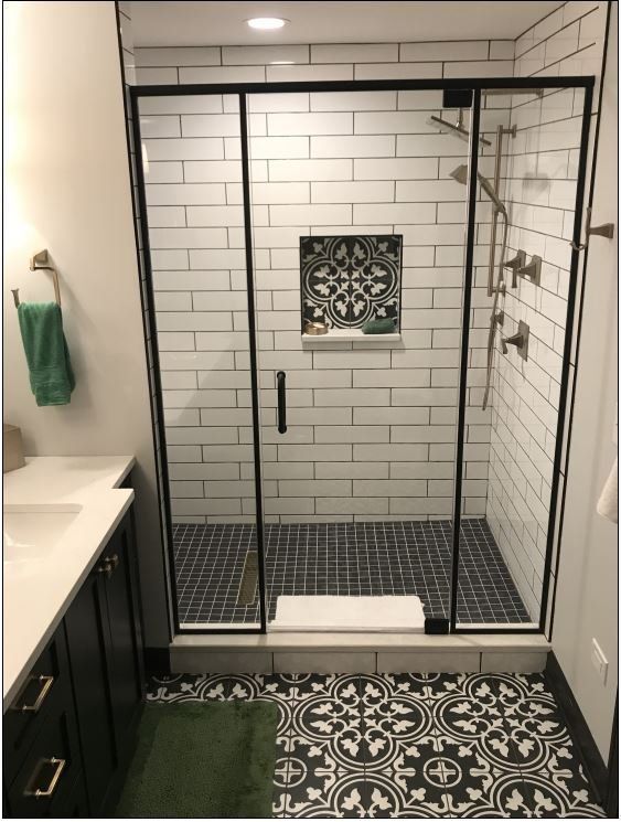 A bathroom with a walk in shower and a black and white tile floor