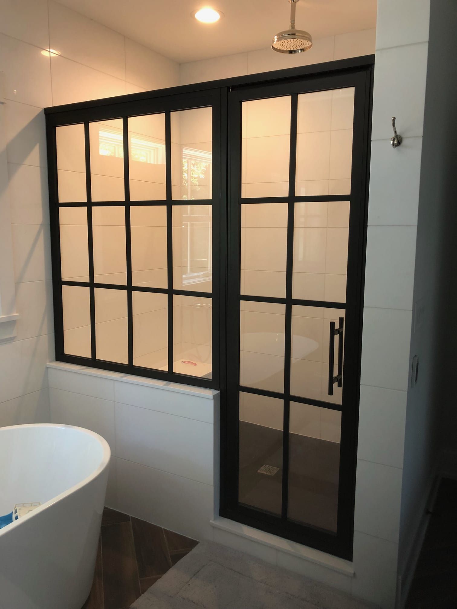 A bathroom with a black shower door and a bathtub