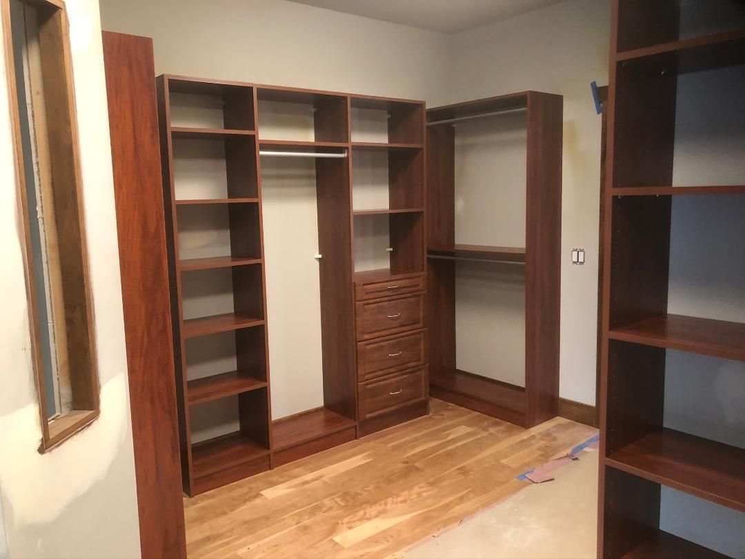 A walk in closet with wooden shelves and drawers