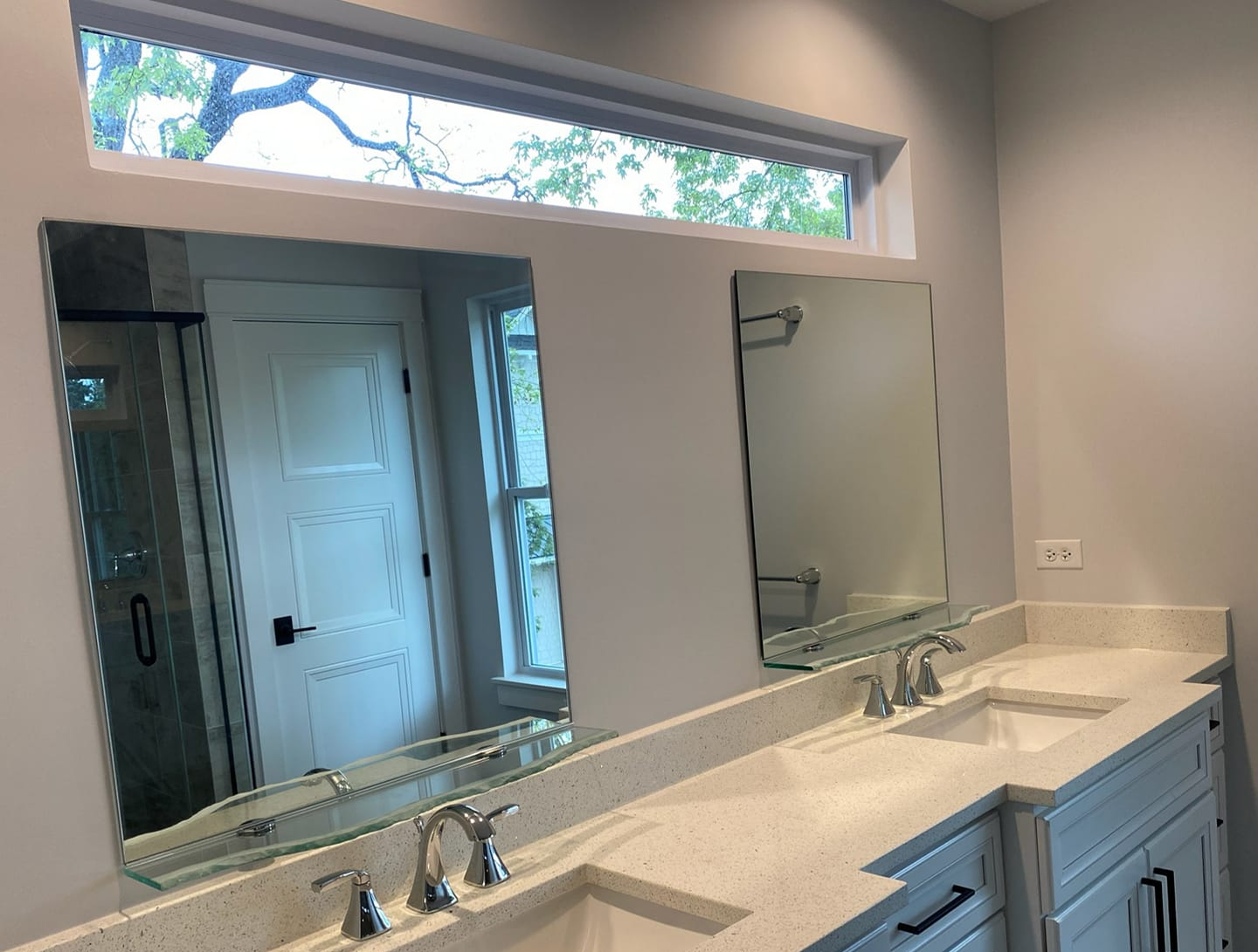A bathroom with two sinks , two mirrors and a window.
