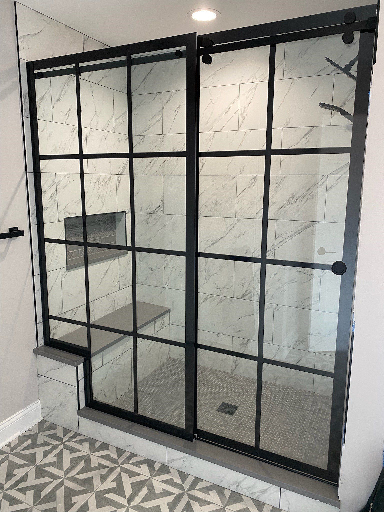 A bathroom with a sliding glass shower door with a black frame.