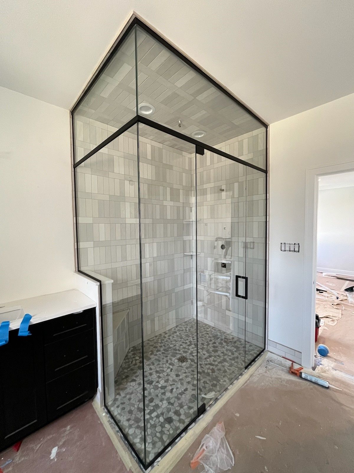 A bathroom with a walk in shower and a black frame.