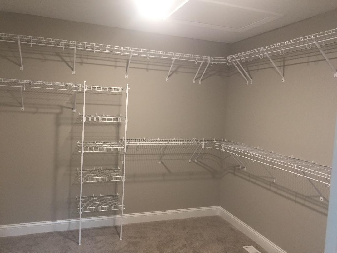 A walk in closet with lots of shelves and a light on the ceiling.