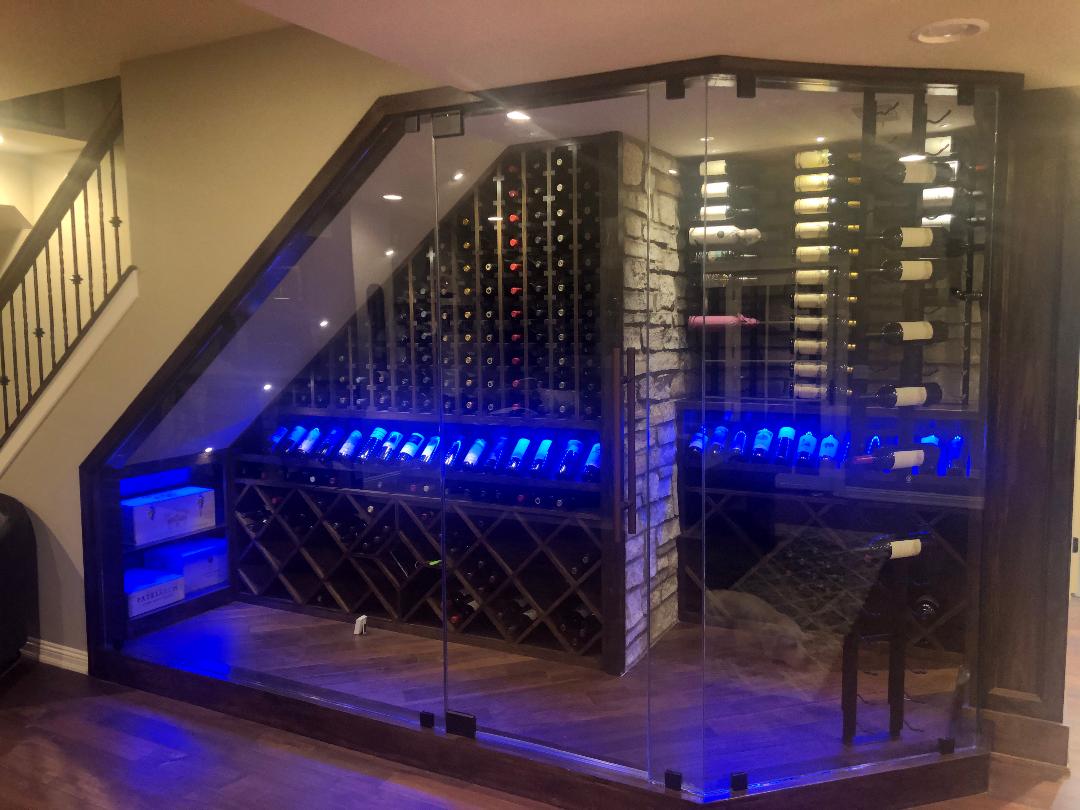 A wine cellar under a staircase with blue lights.