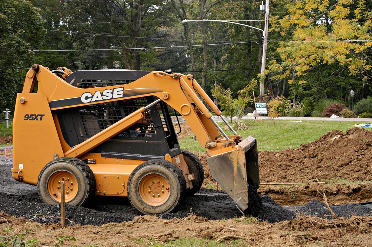 A roll of sod being unrolled onto a patch of dirt and grass. Green grass and brown soil are visible.