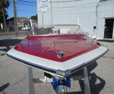 A red and white boat is sitting on a table in front of a building.