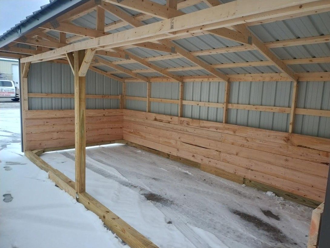 Wooden carport with metal roof and snow-covered ground.