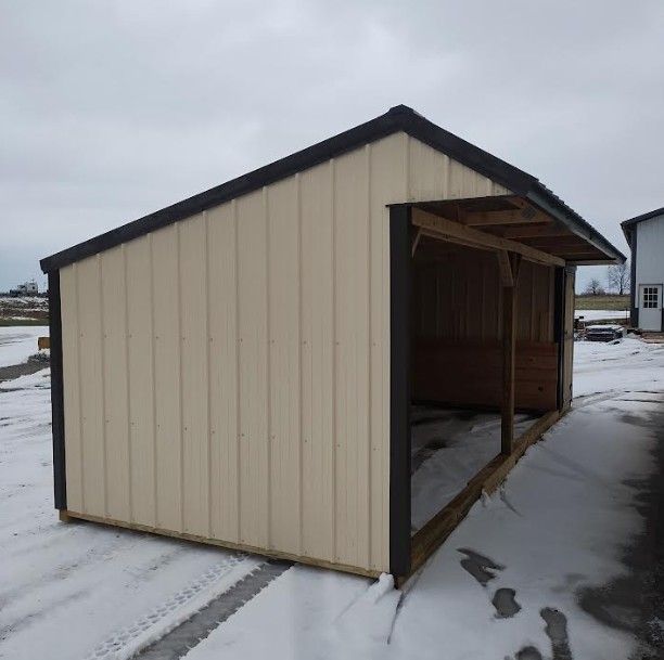 Tan and brown shed with a covered opening, sitting in snow.