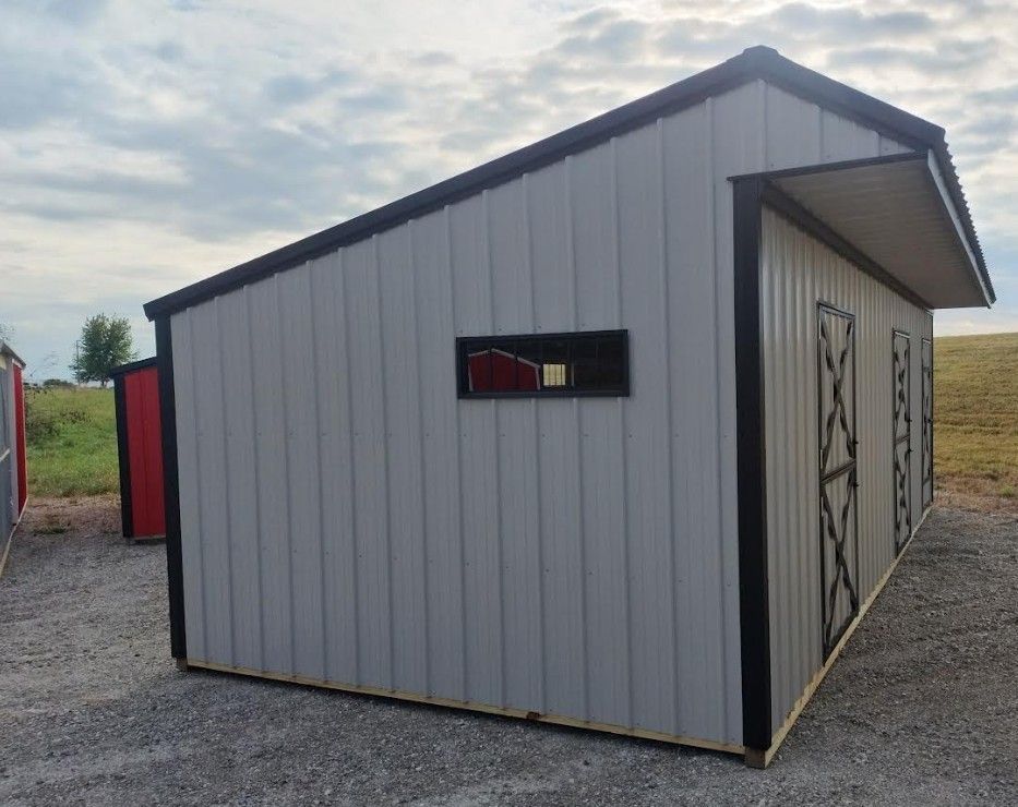 Gray metal shed with black trim and doors, small window, and gravel ground.