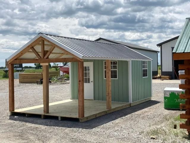 A green shed with a porch and a roof