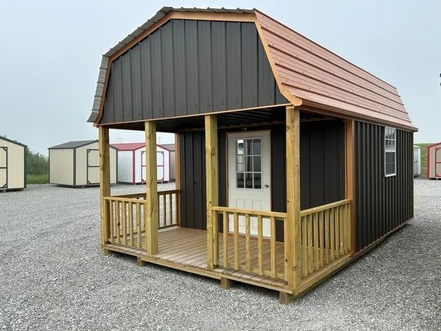 A small house with a porch and a roof is sitting on top of a gravel lot.