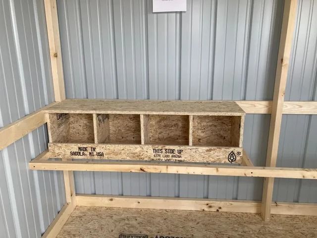 A chicken coop with a wooden shelf and a wooden nest box.