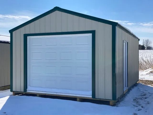 A shed with a garage door is sitting in the snow.