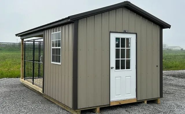 A small shed with a porch and a door is sitting on top of a gravel lot.